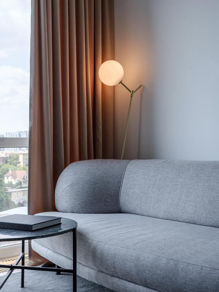 grå 2-sits soffa golvlampa mässing beige gardin