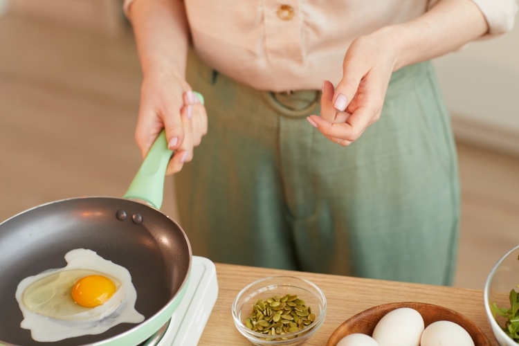 Kvinnan lagar stekt ägg till frukost