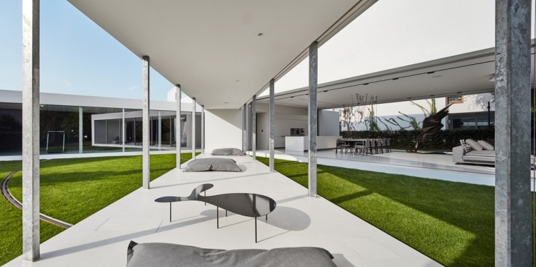 vit och grå trädgård skjul betongbjälkar natursten kakel sittdynor soffbord metall glas glas glasfronter