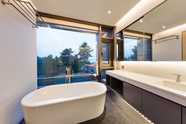 vit grå badrum fristående badkar indirekt belysning fönster