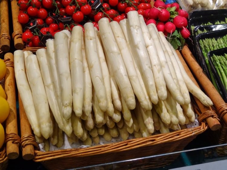 Växande sparris-säljer-på-marknaden-vita-korg-grönsaker-tomater