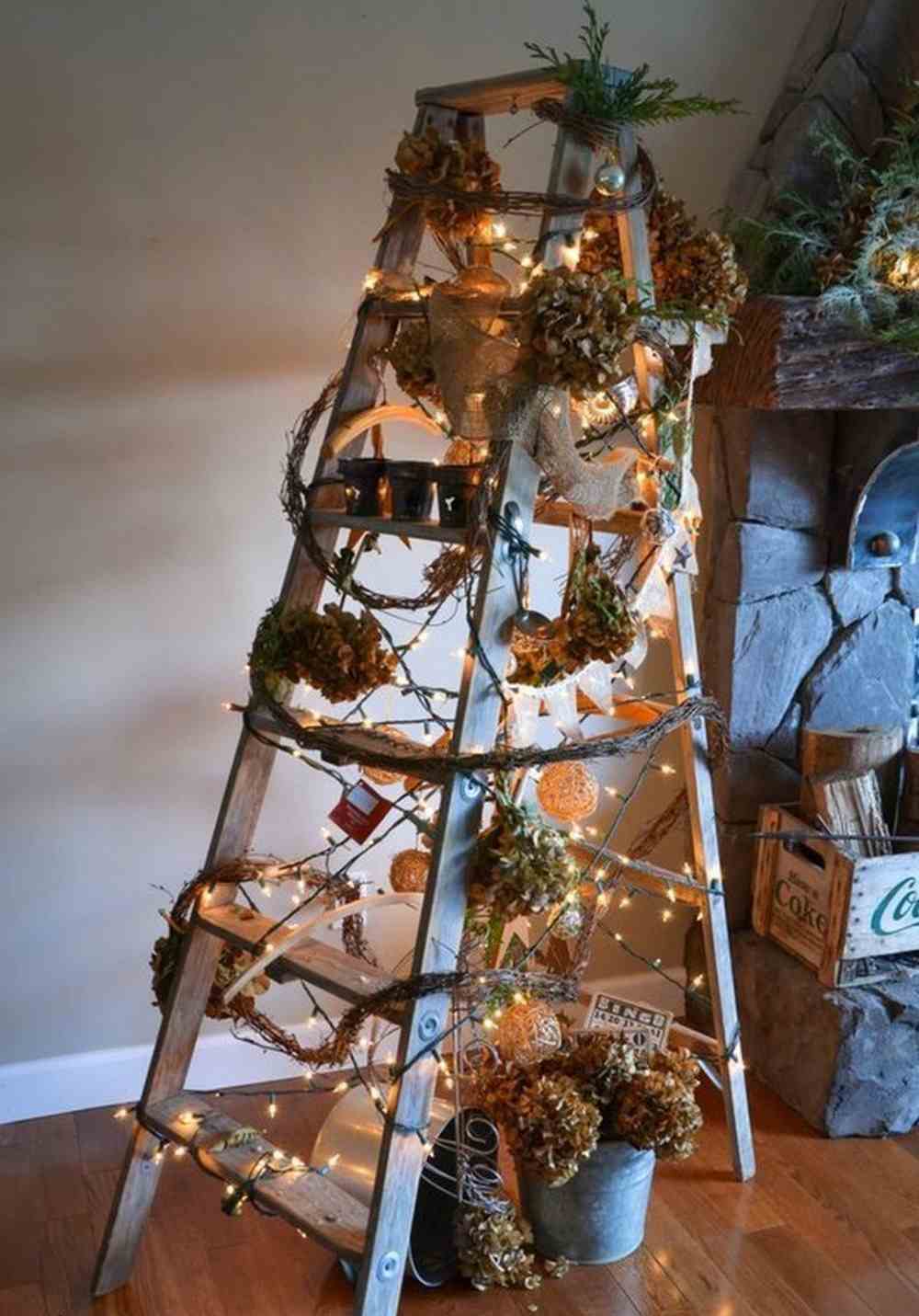 Gör en stege som julgran av trä och dekorera med kransar och kedjeljus samt kottar