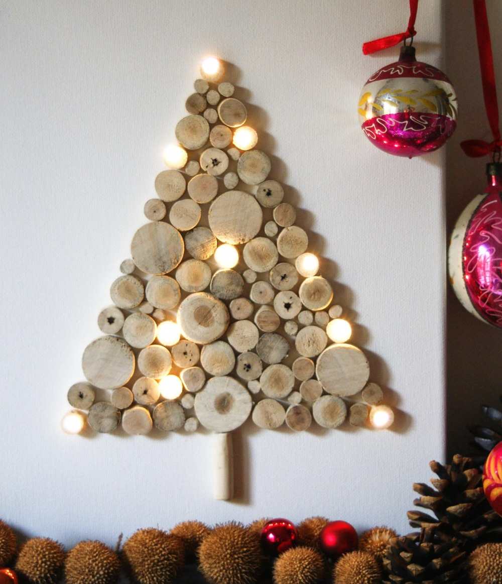 gran av träskivor med LED -lampor fästa på väggen med julbollar