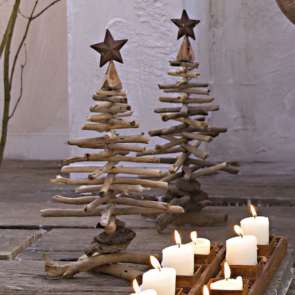 små diy granar av drivved med julstjärnor i rustikt utseende bredvid brinnande ljus
