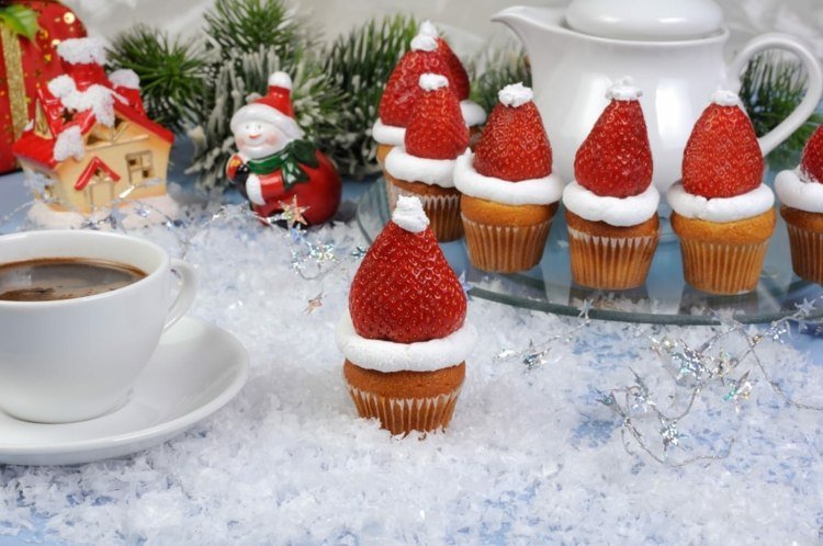 Muffins eller muffins med frosting och jordgubbe i jultomteutseende