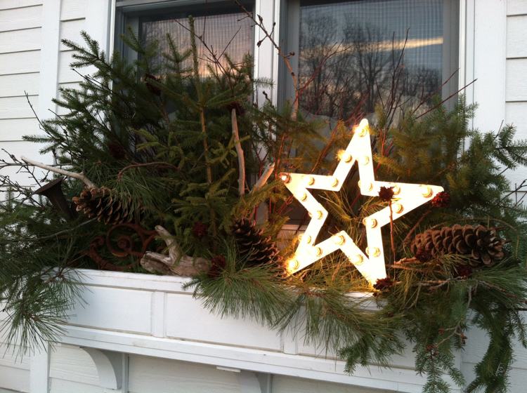 Windowsill utanför dekorera till julstjärna med lampor och långa kottar och tallgrenar och drivved