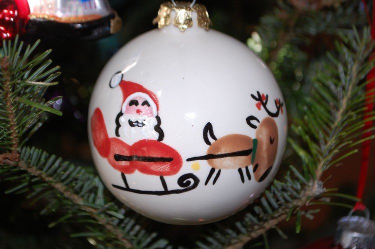 Jultomten i en släde och renar målade med fingeravtryck på julkulor