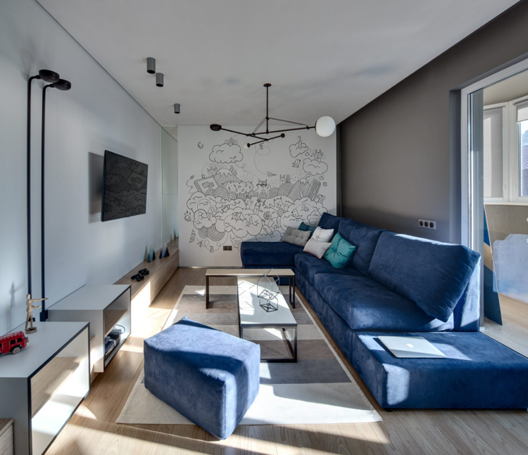 Grå väggar och ljusa trägolv matchar den blå soffan