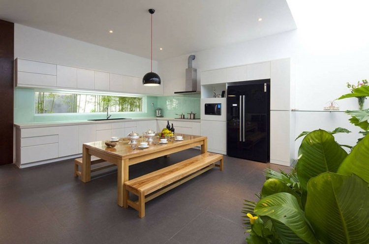 Öppet kök med pastellgrön bakvägg och minimalistisk skåpdesign