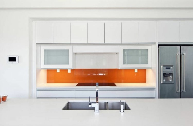 Orange kök bakvägg och vitt kök av glas för ett modernt utseende i rummet