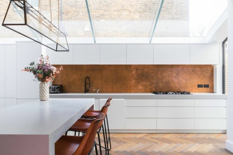 Köksvägg i vitt kök med koppar för en modern och varm atmosfär och som en färg accent
