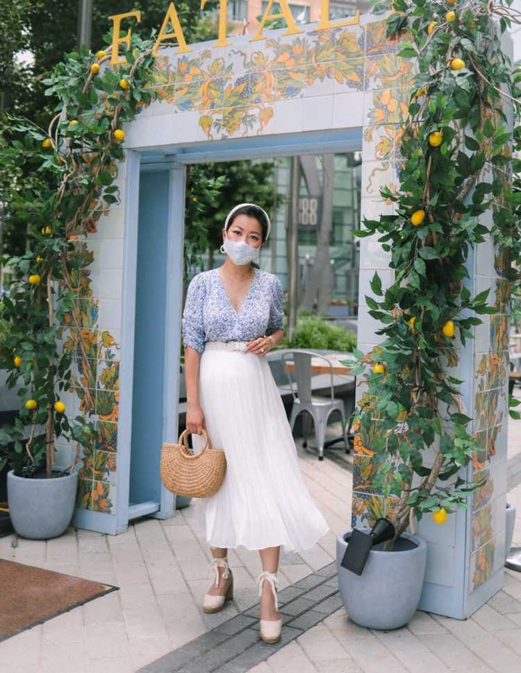 vit veckad kjol på sommaren med mönstrad blus och kilar espadriller