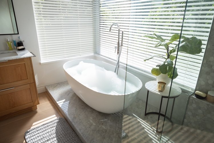 badrum med badkar och persienner i aluminium