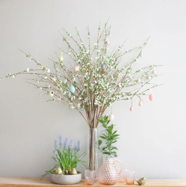 Modernt arrangemang för påskbusken av vita blommor i en smal glasvas