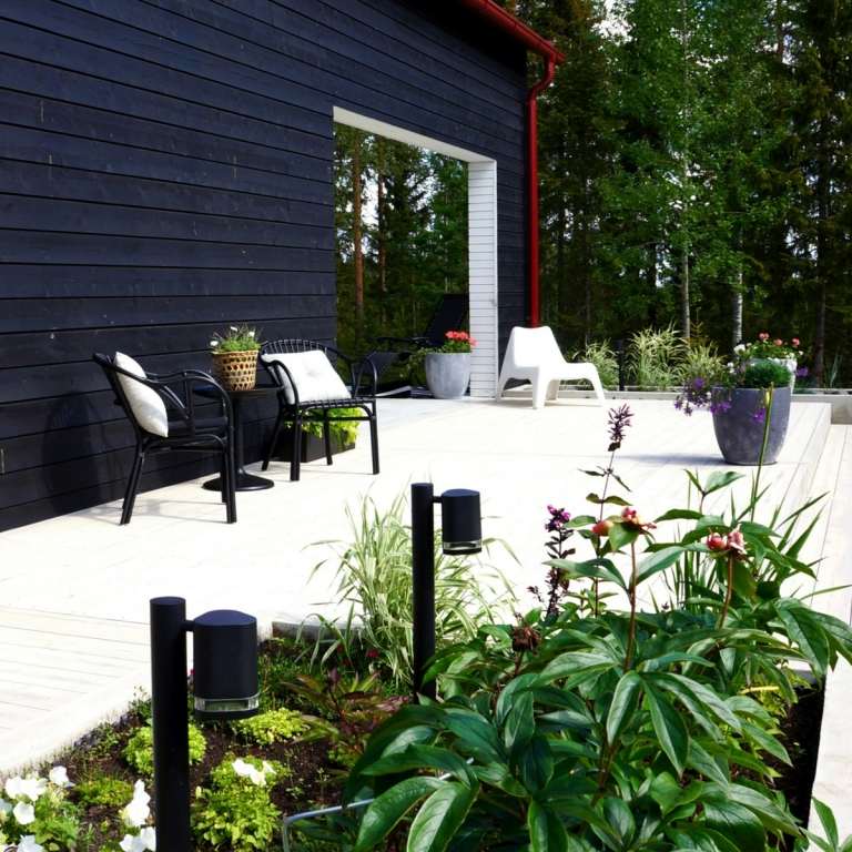Små sängar och planteringar ger den enkla terrassen en naturlig känsla
