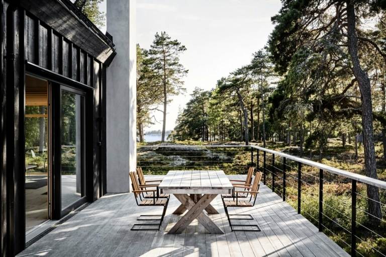 Hög terrass för ett minimalistiskt skandinaviskt hus i svart med vittrad möbeldesign
