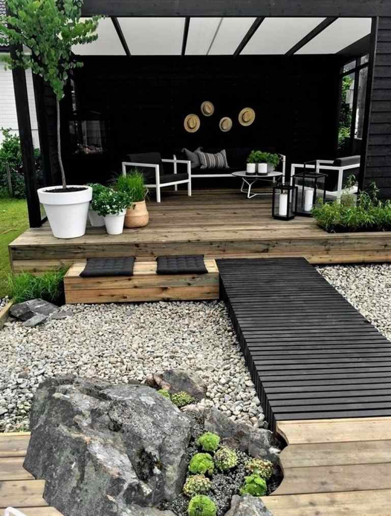 Terrassmöbler i vitt och svart under en modern pergola och växter som dekoration