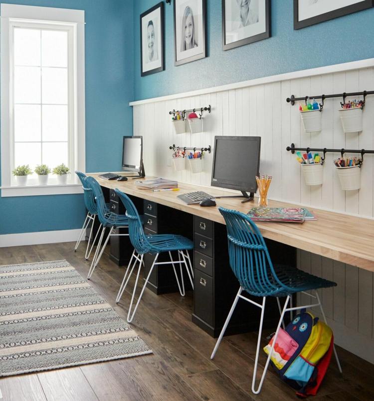 Långt skrivbord på en blå vägg med datorer