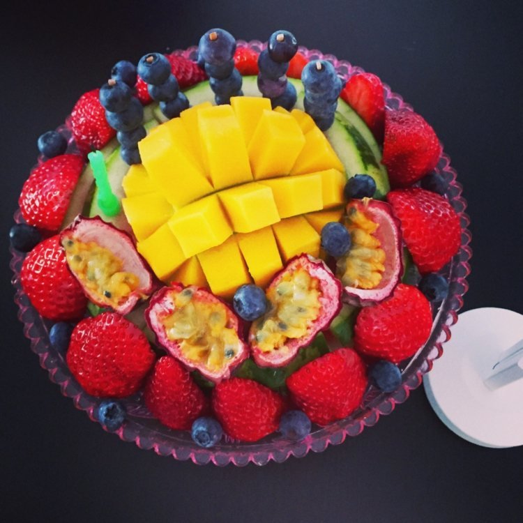 Liten fruktkaka med mango, fikon, blåbär, jordgubbar och ljus