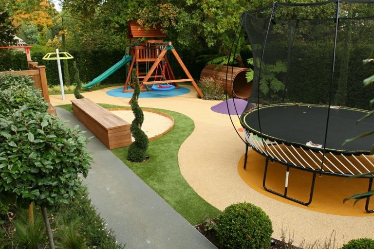 Lekplats för barnen i trädgården med rutschkana, gunga och studsmatta