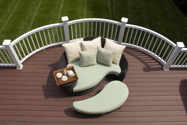 Terrass med snygga loungemöbler, pall, träbricka, kudde, grädde