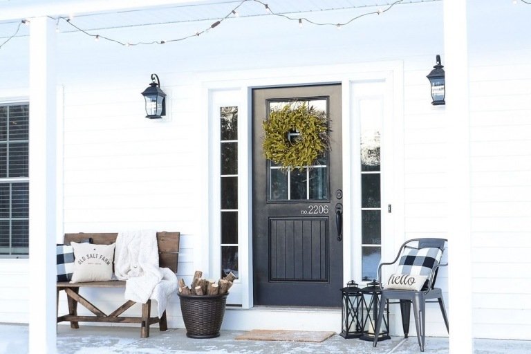 Dörrkrans av lagergrenar och ljuskedja dekorerar husets entré i en puristisk vinterig stil