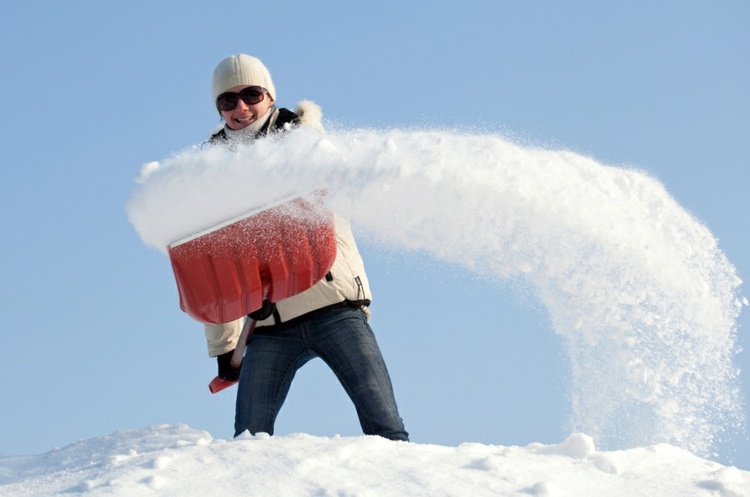 vinter-service-snöröjning-kvinna-le-vinter-kläder-kall-jacka-hatt-vit-jeans-snö-spade.jpg