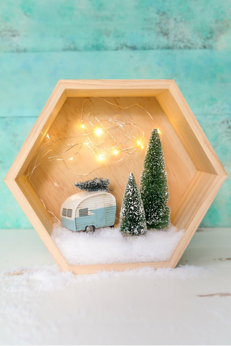Tinker vinterlandskap i en sexkantig låda med husvagn, sagoljus och granar