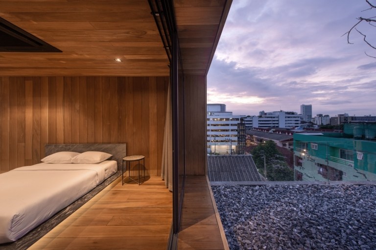 sovrum med dubbelsäng och skjutdörr i glas med utsikt över lägenheten på taket