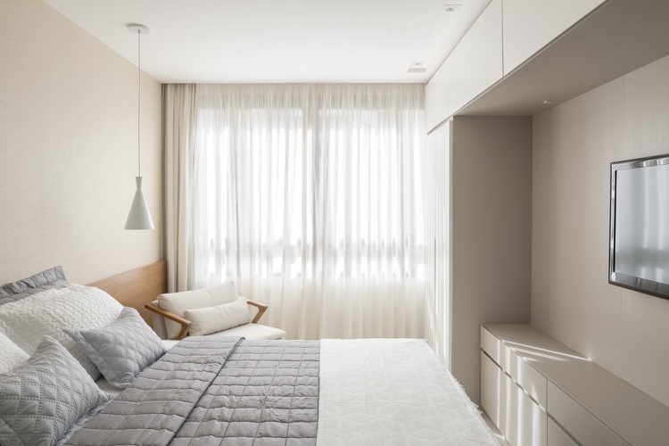 Modern inredning av sovrummet, krämig väggfärg och inbyggd garderob och dubbelsäng med trägavel