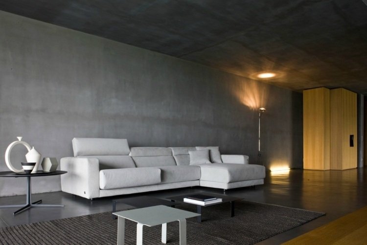 vardagsrum-grå-hörn-soffa-wess-betong-vägg-belysning-matta-minimalistisk-design