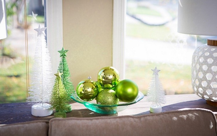 Dekorera soffbordet till jul med en skål med gröna julgranskulor och konstgjorda julgranar