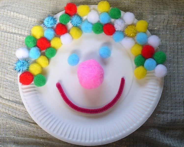 Carnivalclowner gör hantverk av papperstallrikar och pomponger