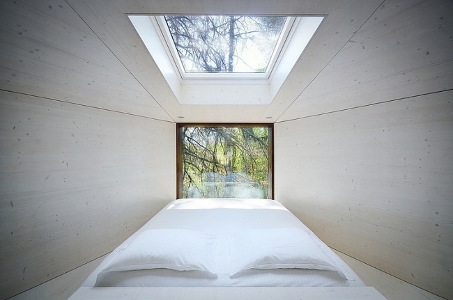 moderna bergstugor säng takfönster trädtoppar utsikt